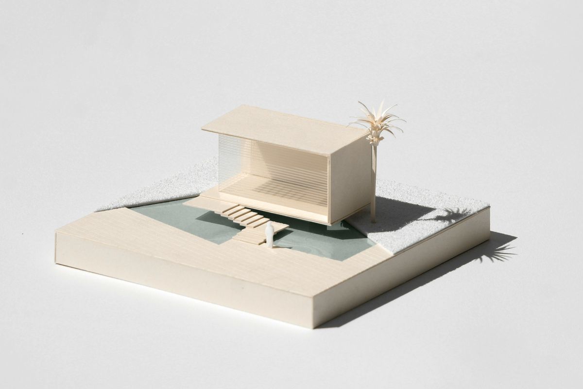 Een witte maquette van een kleine woning met een plat dak op een sokkel.