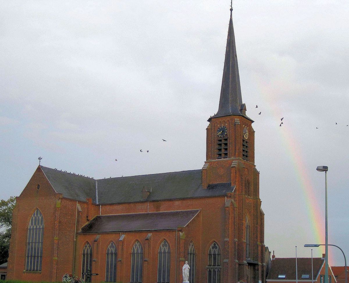 De bakstenen kerk Sint-Jan in de Olie in Vremde, met een regenboog achter de toren.